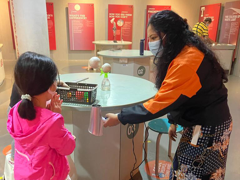 Archana (right) demonstrating a science concept by keeping a ball aloft with a hairdryer.