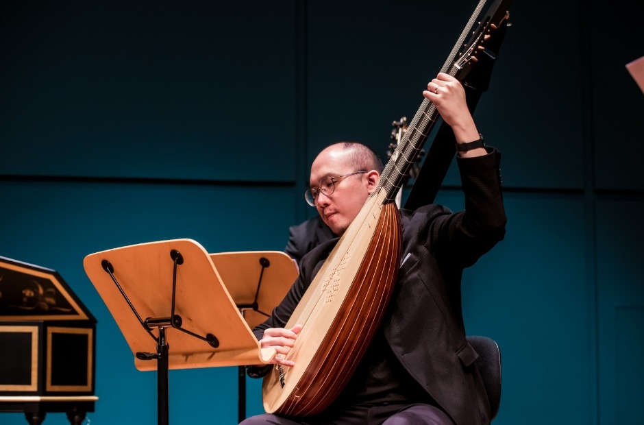 Christopher plays the theorbo (above) and other music instruments; he sees music-making as a conversation between man and machine, no different from how humans are working with AI. (Photo credit: Moonrise Studio)