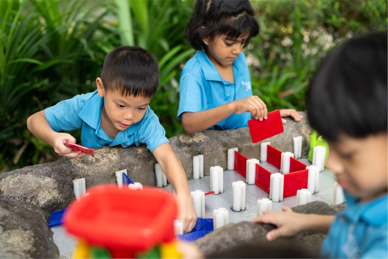 kindergarteners playing with toys to build a plastic wall